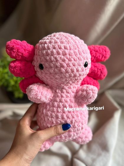 Holding our handmade axolotl toy. It's lightweight and squishy, perfect for hugs and imaginative play.