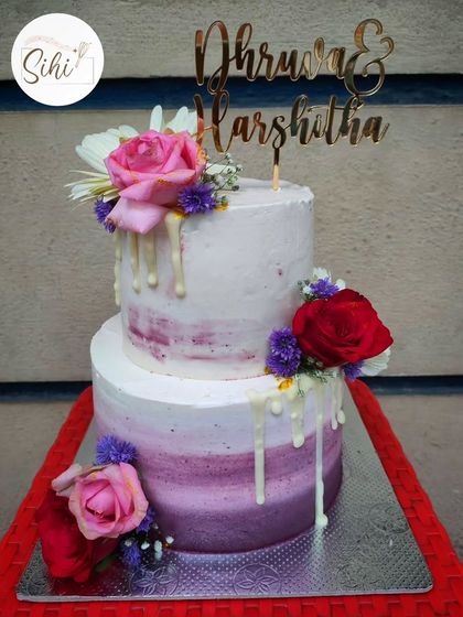 This two-tier engagement cake combines a beautiful purple ombre effect with a white chocolate drip and fresh flowers. It's a modern and vibrant design perfect for a stylish celebration.