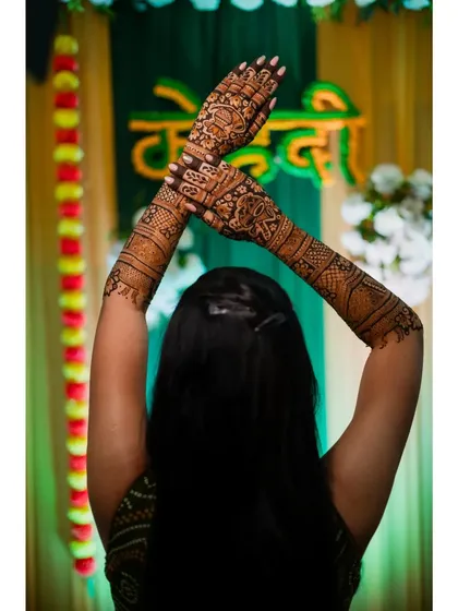 A beautiful shot of the bride from behind, with her arms raised to display the full extent of her intricate mehendi design.