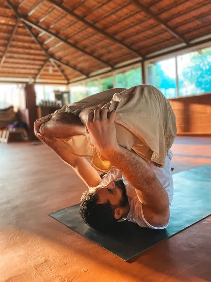 A student practices Urdhva Mukha Paschimottanasana, a challenging seated balancing pose. Our training provides the tools and support to work towards such advanced asanas.