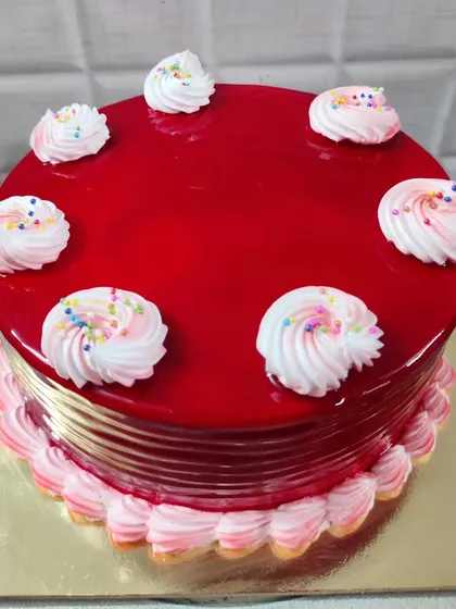 This strawberry cake is as bright and cheerful as it tastes. It has a shiny red strawberry glaze and is decorated with simple swirls of pink and white frosting topped with rainbow sprinkles.