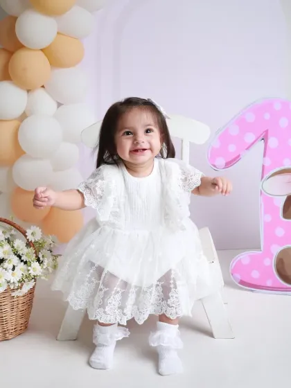 A huge, happy smile for her first birthday portrait. Dressed in a lovely white lace dress, she is the star of the show.