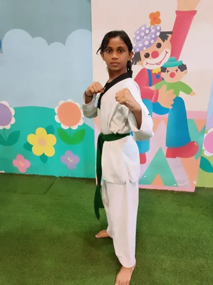 This young green belt is ready for action. Her strong stance and focused gaze show she's prepared for her training.