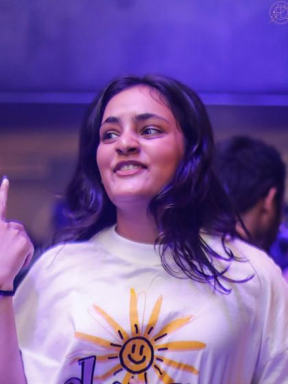 A partygoer with a sunny disposition, pointing up and enjoying the music.