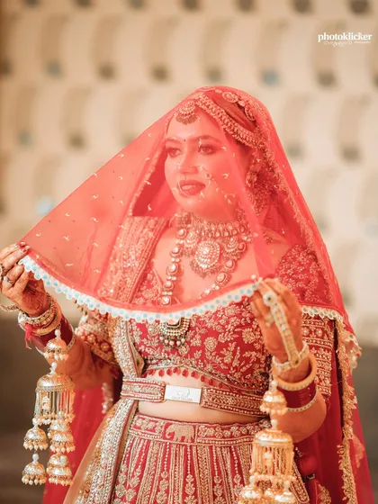 A classic bridal portrait, with the bride gently lifting her veil. This shot highlights her beautiful jewelry, makeup, and the traditional kaleeras.