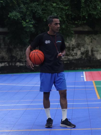 A coach stands on the court, ball in hand, ready to lead. Our expert coaches are here to guide you on your basketball journey.