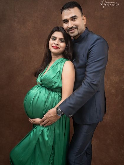 A powerful and elegant pose. The contrast between her vibrant green gown and his classic suit makes for a striking and beautiful couple's maternity portrait.