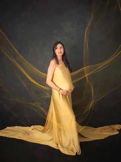 A truly radiant solo portrait of a mom-to-be. The flowing golden gown and ethereal fabric effects create a powerful and elegant image, celebrating the strength and beauty of motherhood.