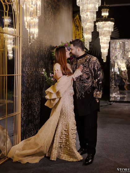 A romantic kiss shared by Simran and Sammy, framed by grand chandeliers at their reception.
