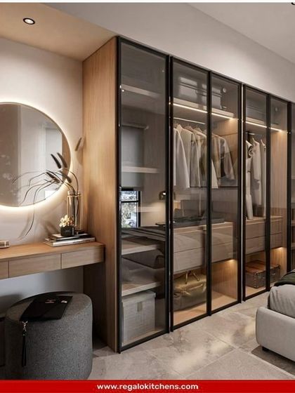 We integrated a full vanity table into this wardrobe design, complete with a lit circular mirror. The glass doors offer a peek at the organized interior, blending functionality and style.