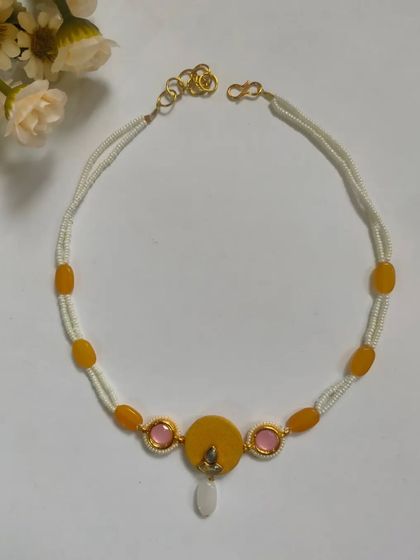 A delicate necklace made with strings of white beads and accented with yellow and pink stones. This is a great choice for those who prefer subtle, elegant jewelry for weddings or parties.