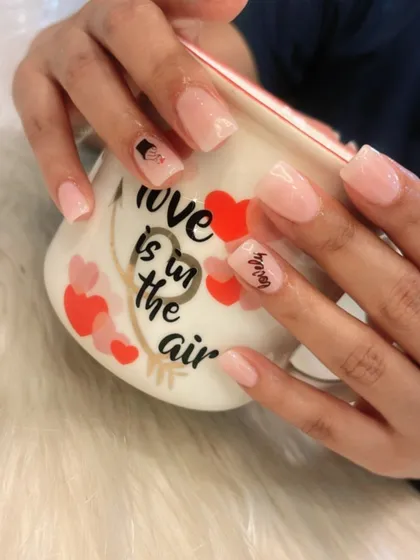 A sweet and simple manicure with a milky pink base and cute "love" themed stickers.