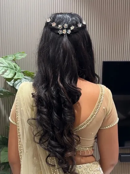 A beautiful half-up hairstyle with dreamy waves and dainty floral accessories, perfect for a soft glam engagement look.
