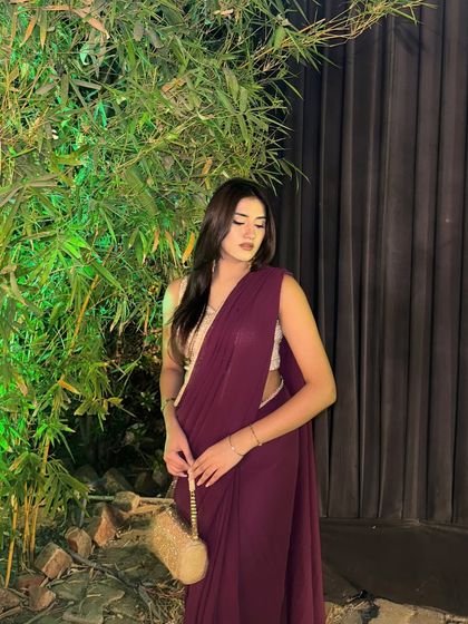 A candid moment captured in the saree, looking away from the camera. The focus is on the outfit's silhouette and the soft lighting.