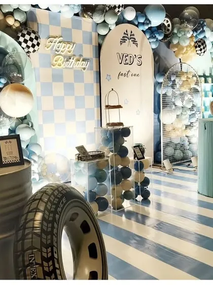 For Ved's "fast one," we went all out with a race car theme. This setup features custom backdrops with checkered flags, a striped floor for the "racetrack," and even a real tire prop to make the birthday boy feel like he's at the Grand Prix.