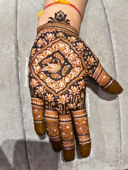 This design fills the entire palm with a central peacock motif surrounded by a dense pattern of lotus flowers, using negative space to make the figures pop.