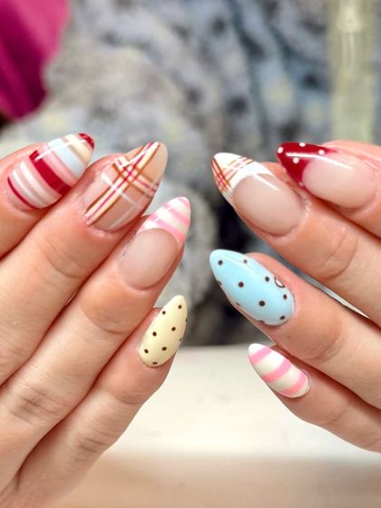 Soft shades and sweet details give these nails major Valentine energy. This mismatched set features stripes, plaid, and polka dots in a romantic color palette of red, pink, blue, and cream.