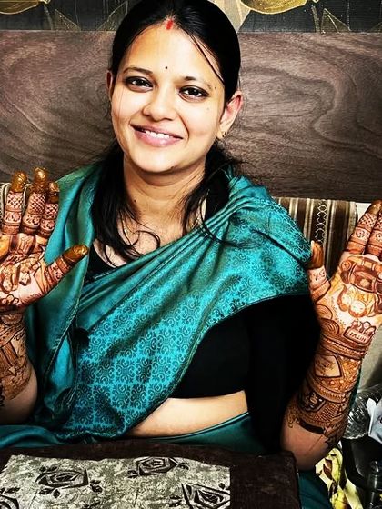 A happy mom-to-be showing off her intricate baby shower mehndi. The design is filled with traditional patterns and symbols celebrating the new life to come.