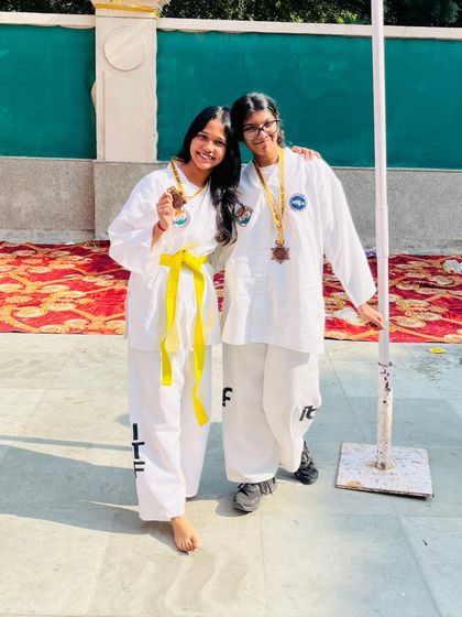 Two teammates celebrating their medal wins together at the Delhi State Championship.