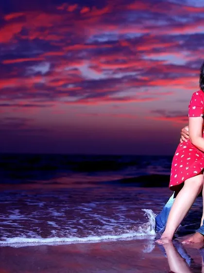 A passionate kiss shared by a couple on the beach as twilight paints the sky in dramatic shades of red and purple. This shot captures the raw emotion and romance of a seaside pre-wedding session.