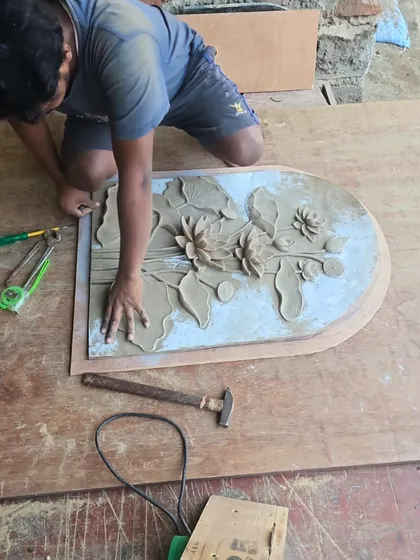 A member of my team works on refining the cast of the lotus mural. This stage involves sanding the surface and sharpening the details before the final painting can begin.