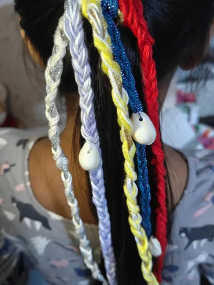 A colorful set of boho hair extensions ready for a customer. I love combining bright threads like red, blue, and yellow with shimmering silver and white shells to create a fun, festive look.