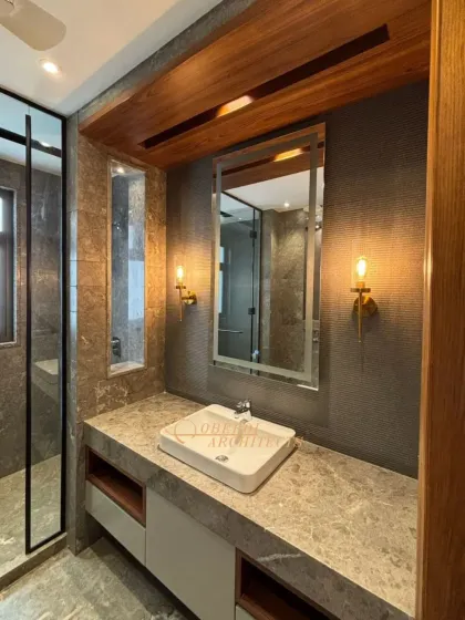 A close-up of the vanity area, with warm sconce lighting that complements the natural tones of the wood and stone.