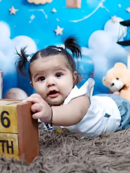 A six-month-old baby girl exploring her surroundings during our teddy bear and clouds themed shoot.
