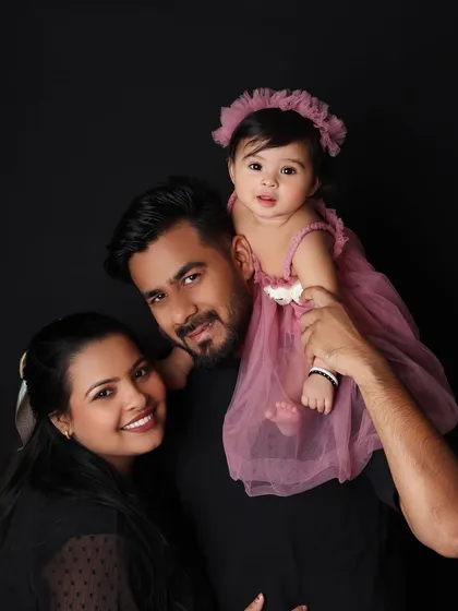 A fun and classic family pose with the baby sitting on her father's shoulders. This portrait captures the playful and joyful side of being a new family.