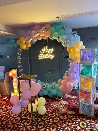 A side view of the pastel rainbow decor, highlighting the depth of the balloon arch and the glowing name blocks.