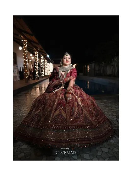 A stunning night-time bridal portrait by the pool, the bride seated in her full lehenga, looking like royalty.