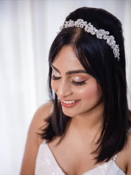 A close-up of the bride's finished look. The soft pink eyeshadow and glowing skin create a romantic and youthful feel, complemented by a delicate crystal headband.
