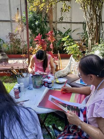 An adult student enjoying our outdoor art session, surrounded by the beauty of the garden as she works on her painting.