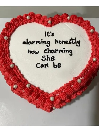 A top-down view of the vintage heart-shaped cake, showing the intricate piping border and the custom message.