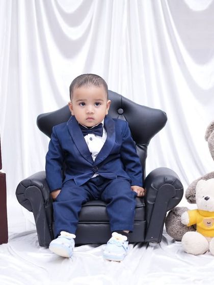 Looking sharp for his first birthday! This little gentleman is dressed in a full suit, sitting like a boss next to "ONE" blocks and his teddy bear friends.