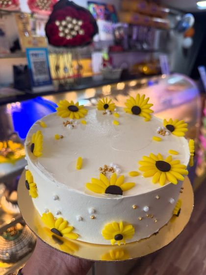 A cheerful sunflower-themed cake. The bright yellow fondant sunflowers are handcrafted and arranged beautifully on a simple white cake, bringing a ray of sunshine to any celebration.