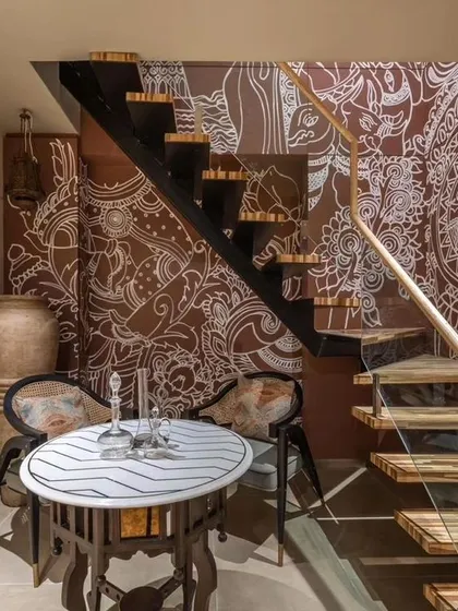 A modern interpretation of traditional Pichwai art for a saree boutique in Surat. The intricate white line work on a rich brown background wraps around the staircase, telling a story of heritage and craft.