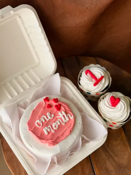 A one-month anniversary celebration combo with a pink bento cake and two cupcakes.