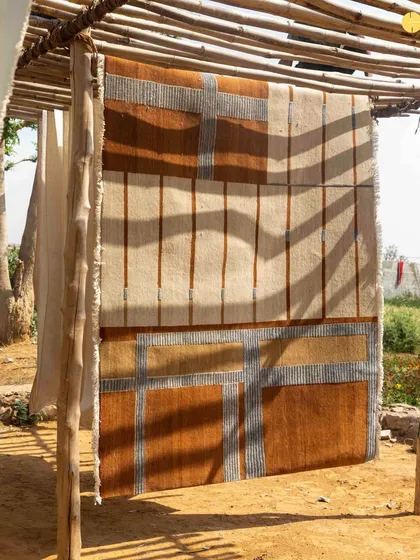 Another rug from the collection, with its geometric patterns echoing architectural forms, drying in the sun.