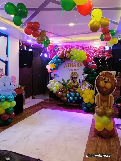 This wide shot shows how the entire space was transformed for the jungle party, with balloon columns, a main backdrop, and ceiling decorations all working together to create an immersive environment.