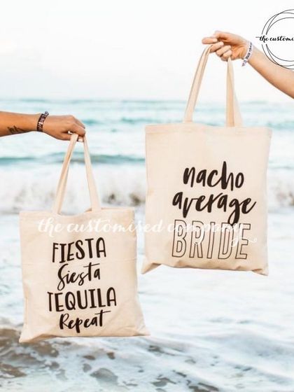 Beach essentials for your bachelorette party. These canvas tote bags feature fun phrases like "Nacho Average Bride" and "Fiesta Siesta Tequila Repeat."