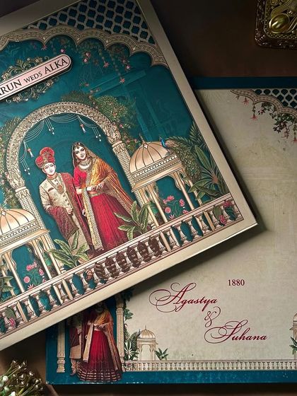 This design features a deep teal background, creating a dramatic contrast for the royal couple illustrated under a beautifully decorated archway.