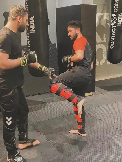 This image captures the intensity of a kick being delivered during a drill. The student is practicing a defensive kick to create space from an advancing opponent.