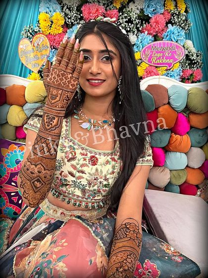 This bride is all smiles as she displays her stunning full arm mehndi. The design is intricate and detailed, a perfect accessory for her beautiful floral lehenga.