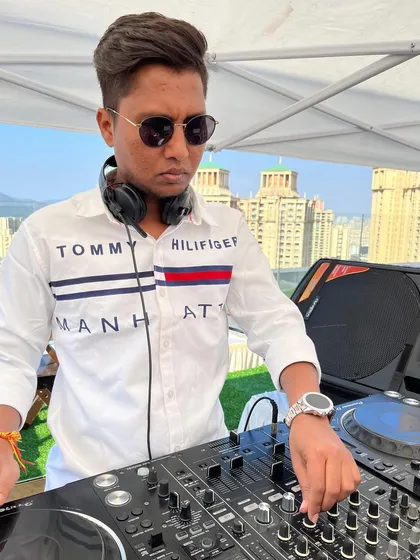 A focused shot of me at a rooftop party with the city skyline in the background. The location often inspires the music I play.