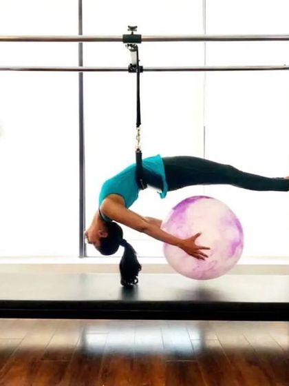 A client performs a graceful backbend over the stability ball on the Cadillac. This exercise opens up the chest and shoulders while strengthening the back.