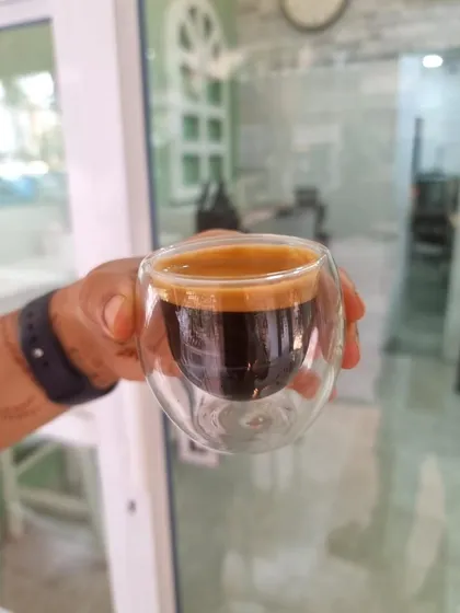 A perfectly pulled espresso shot, held up to the light. You can see the rich color and the thick, stable crema, a sign of a well extracted and high quality coffee.
