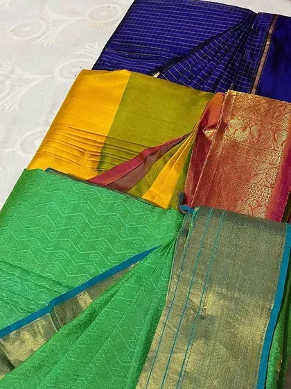A collection of colorful sarees, green, yellow, and blue, ready for folding.