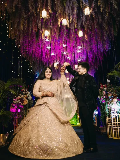 Under a canopy of flowers and lights, the first dance is a moment of pure magic. This shot captures the couple lost in their own world, showcasing the grand scale of their reception decor while keeping the focus on their romantic connection. It’s a perfect blend of ambiance and intimacy.