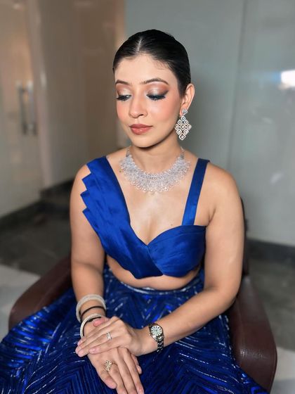 A stunning look in a royal blue lehenga. The makeup features a sharp wing and a clean base, creating a look that is both modern and elegant.